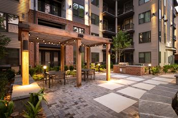 A patio area with a pergola, seating area, and grill